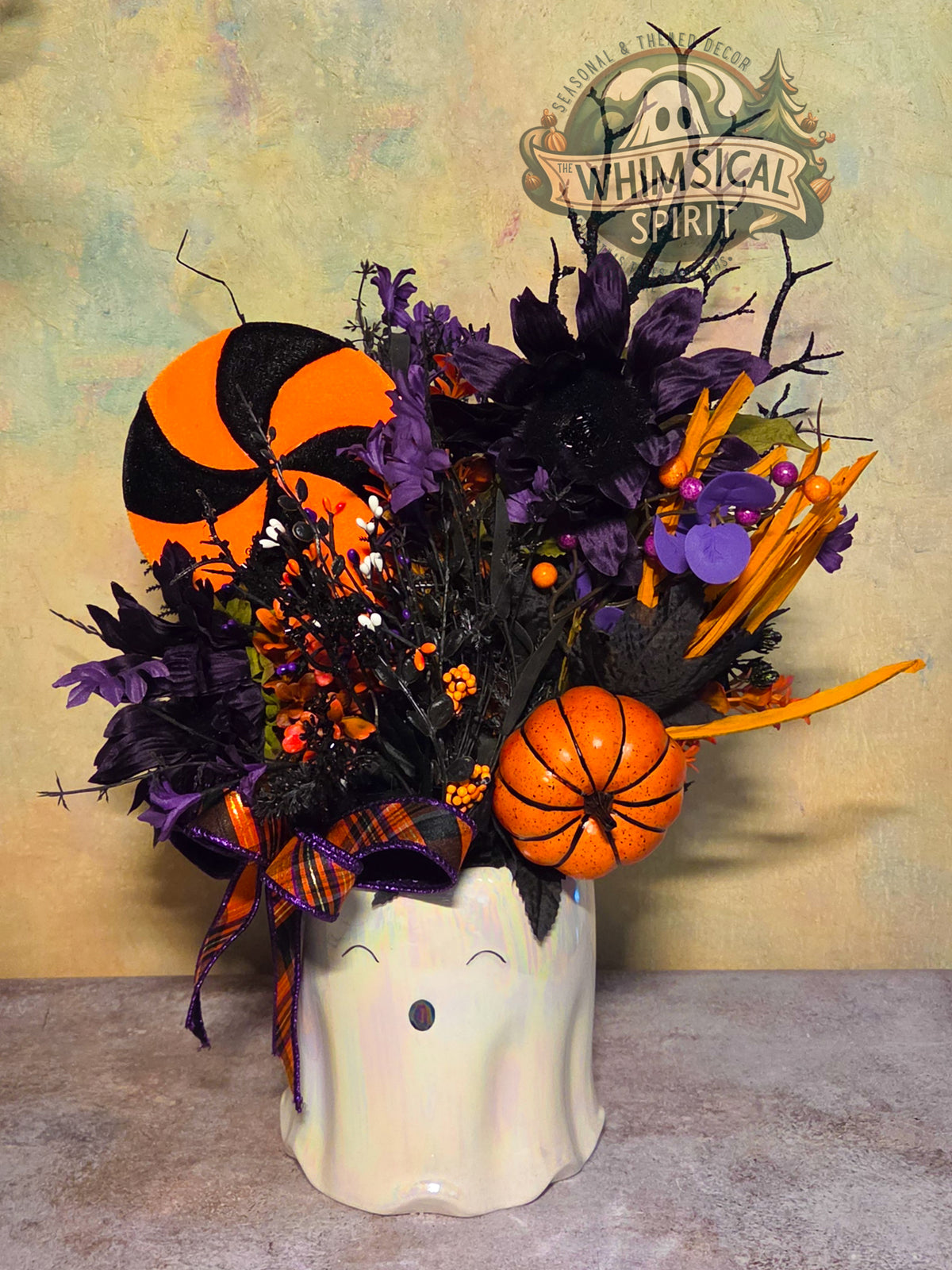Full view of Midnight Booquet with a white ghost vase, dark purple flowers, orange accents, and plaid ribbon.
