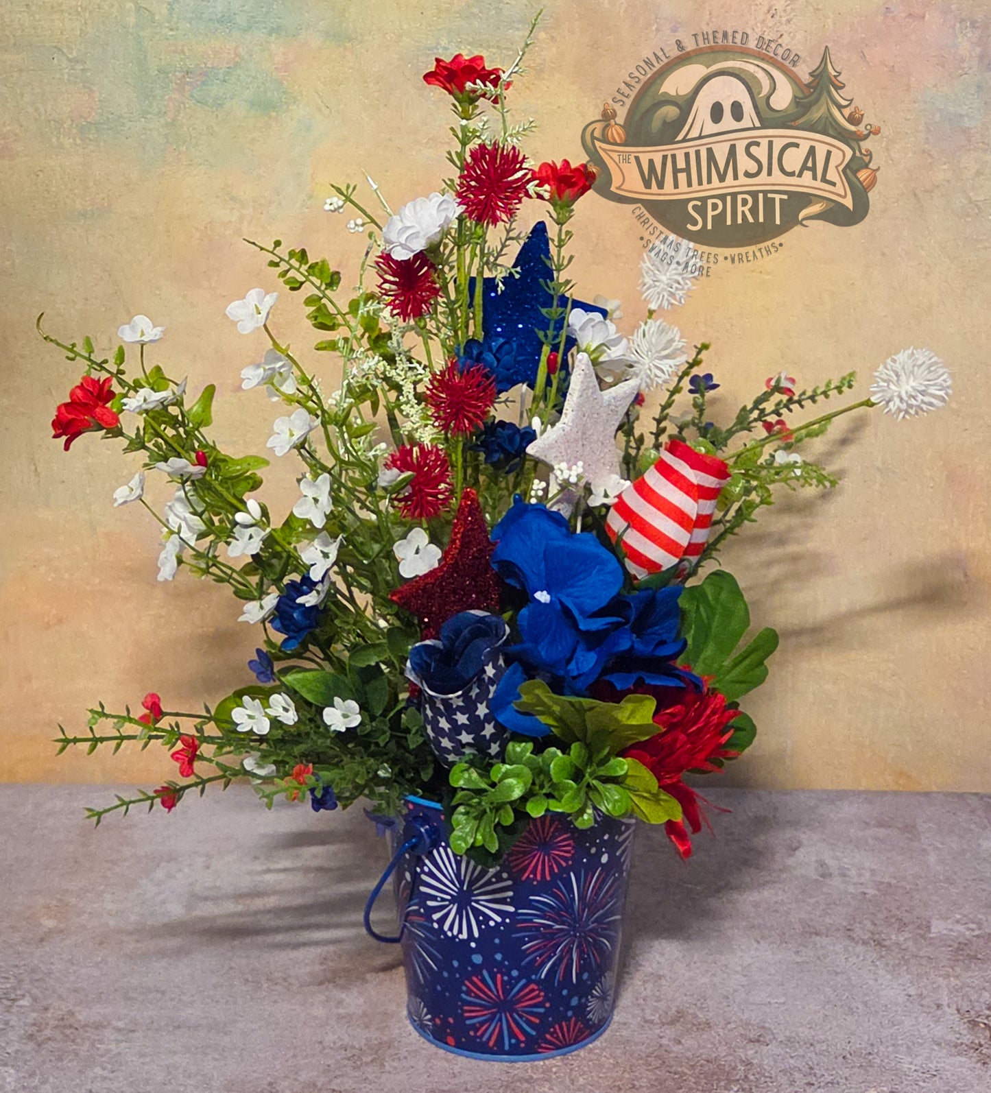 Bouquet with red, white, and blue flowers in a decorative vase on a textured surface with 'Whimsical Spirit' branding.