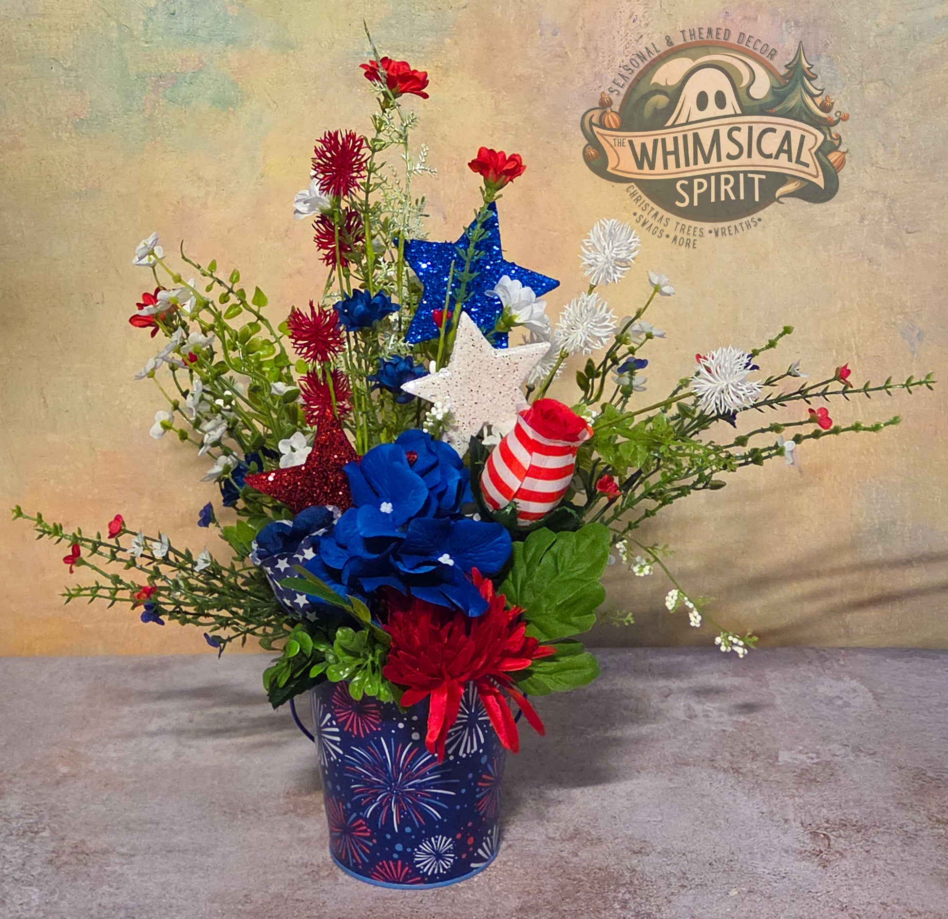 Decorative flower arrangement with patriotic elements in a container, branded 'Whimsical Spirit'.