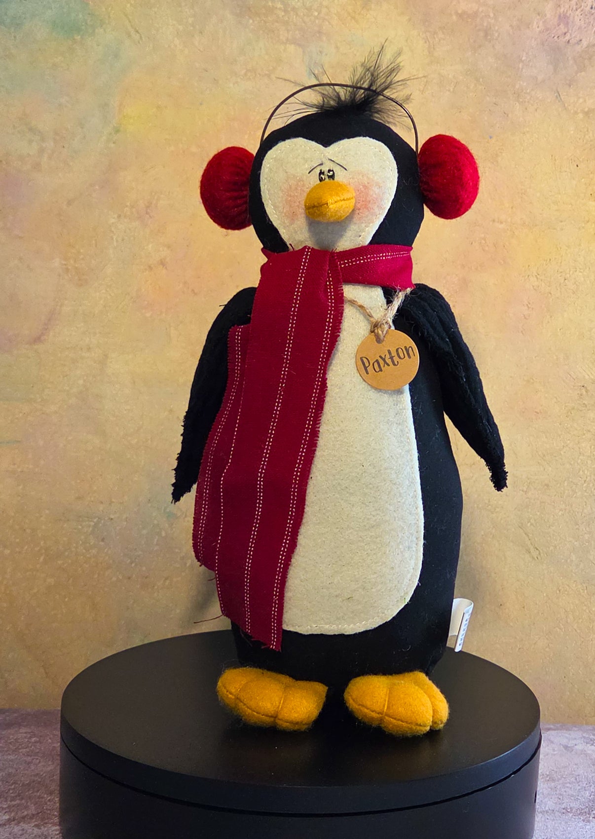 Prince the Penguin winter soft sculpture shelf sitter with gray scarf, plaid winter hat, plush black-and-white penguin body, and name tag.