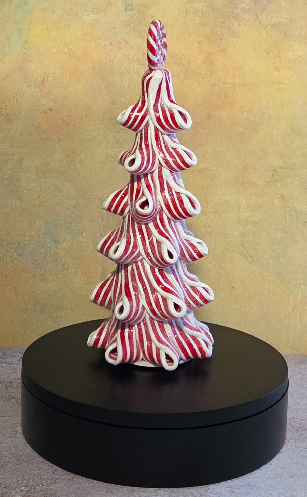 Tall lighted peppermint ribbon Christmas tree tabletop decor with curled red-and-white striped layers and a round peppermint topper.