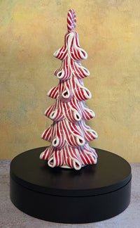 Tall lighted peppermint ribbon Christmas tree tabletop decor with curled red-and-white striped layers and a round peppermint topper.