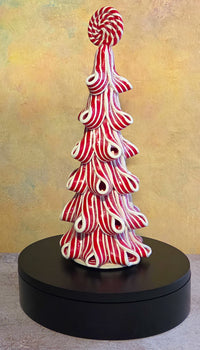 Back view of a lighted peppermint ribbon Christmas tree tabletop decoration showing the dimensional layered design and power access.