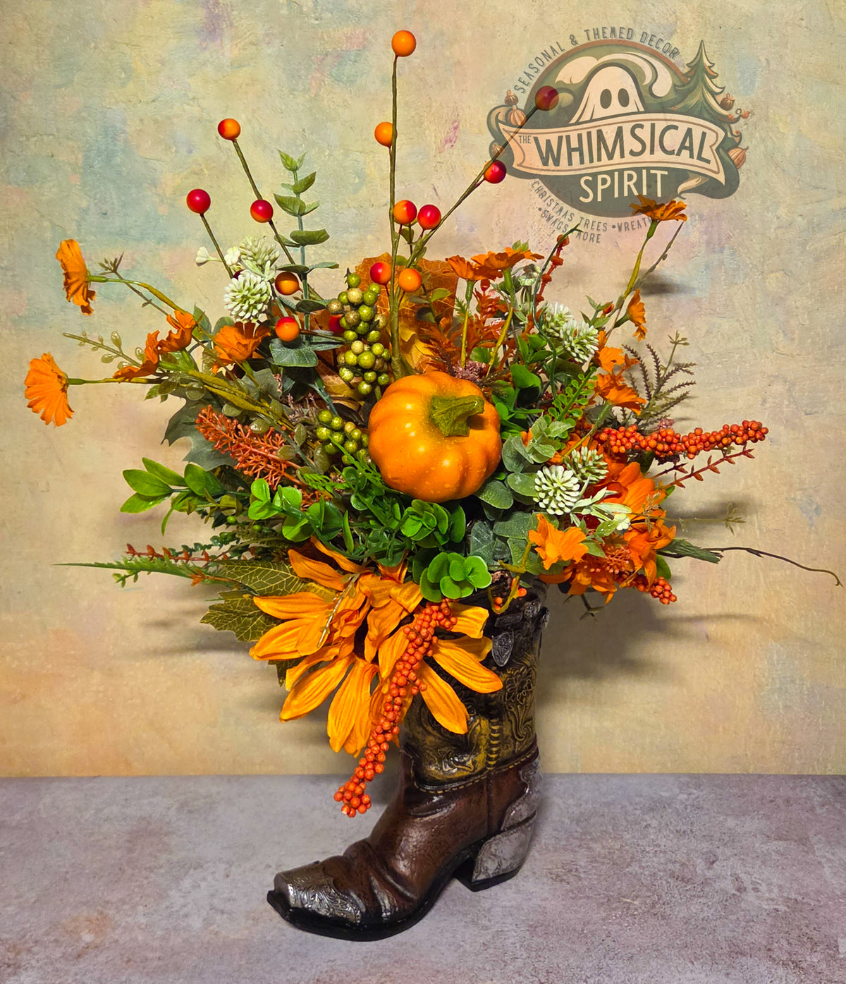 Brown cowboy boot fall centerpiece with an orange pumpkin, orange flowers, greenery, and red, orange, and green berry accents.