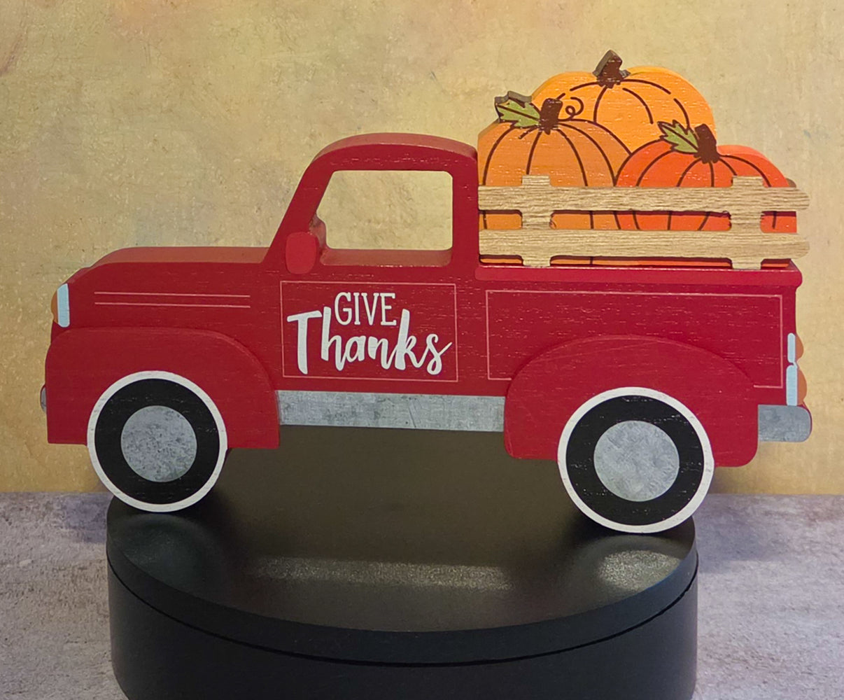 Red pickup truck fall shelf sitter with a “Give Thanks” message on the door and pumpkins in the truck bed.