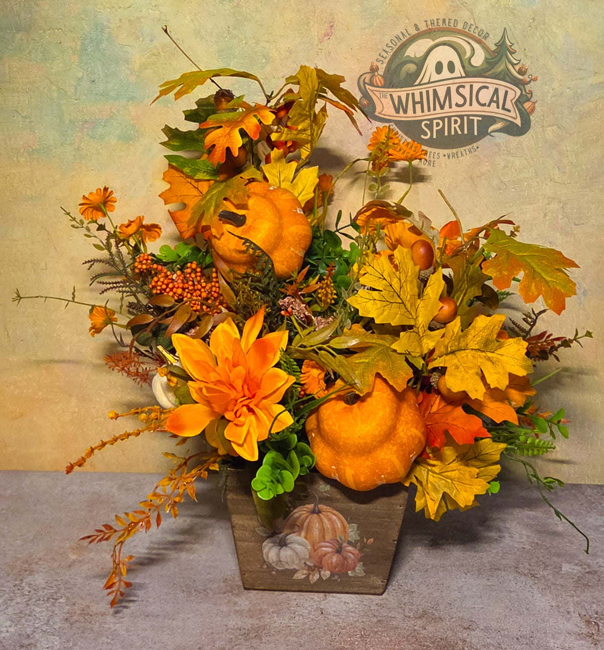 Rustic fall centerpiece with orange pumpkins, an oversized orange flower, autumn leaves, berries, greenery, and a painted wooden box.