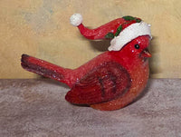 Glittery red Christmas cardinal figurine facing right with an extended tail, textured feather details, and a red Santa hat accented with white trim and green holly leaves.