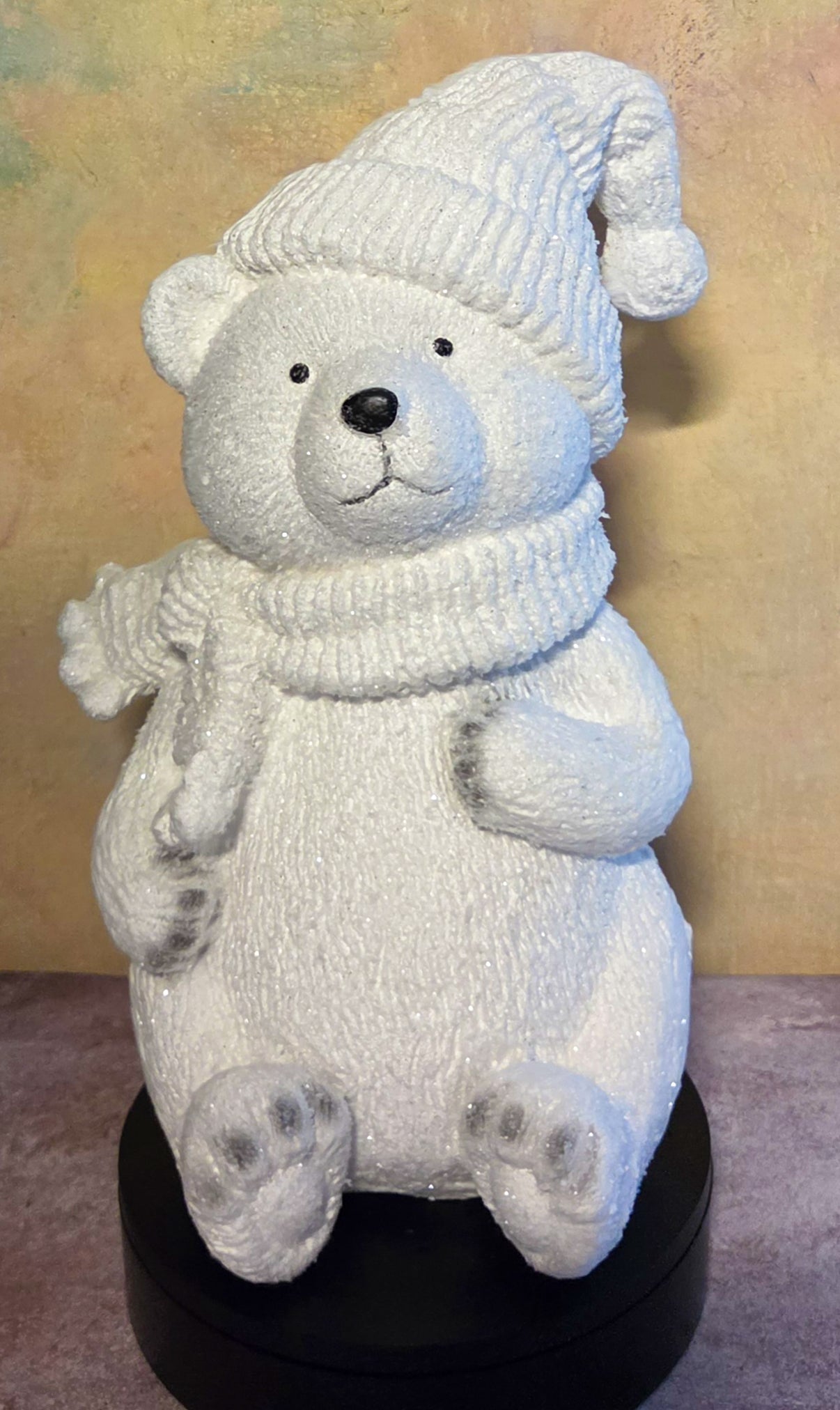 Front view of large white polar bear Christmas figurine wearing a textured winter hat and scarf with sparkling snow-covered details.