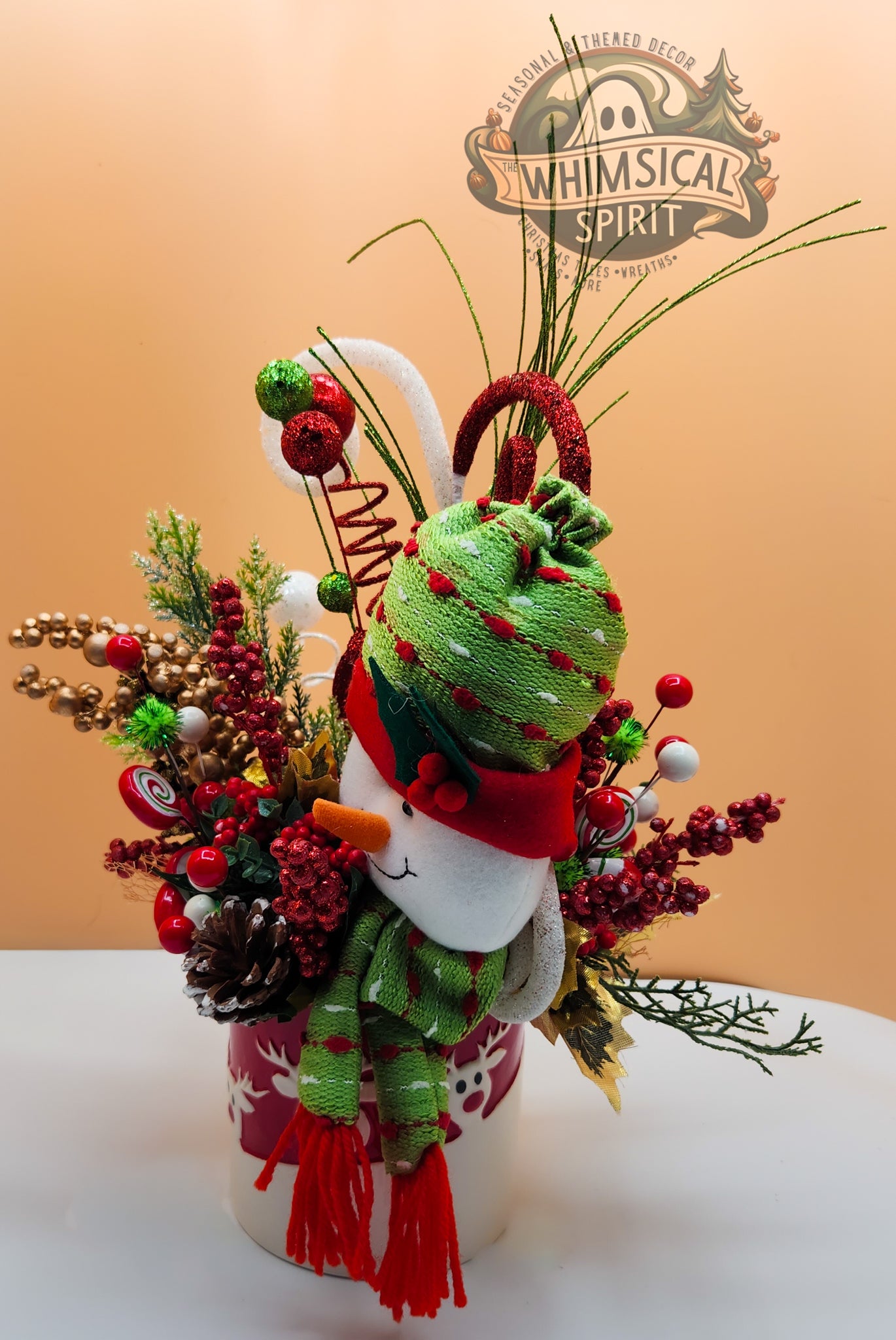 Christmas arrangement with snowman, pine, berries, and ornaments on white surface: Whimsical Spirit