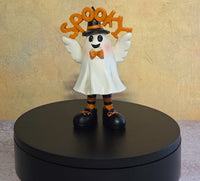 Small white Halloween ghost resin figurine wearing a black top hat, orange bow tie, striped socks, and black shoes while holding a “SPOOKY” sign.