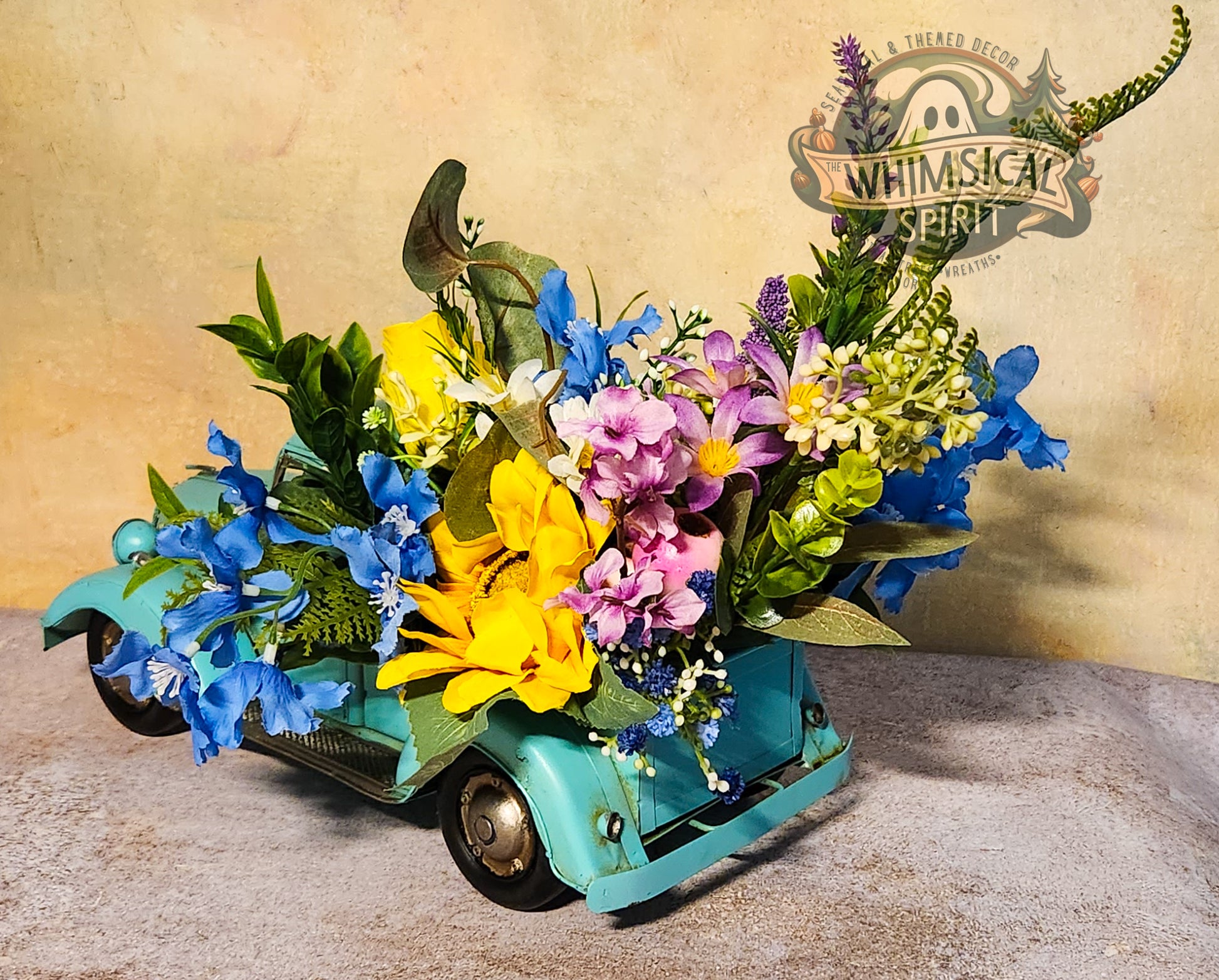 Floral arrangement in a miniature car with 'Whimsical Spirit' branding in the background.
