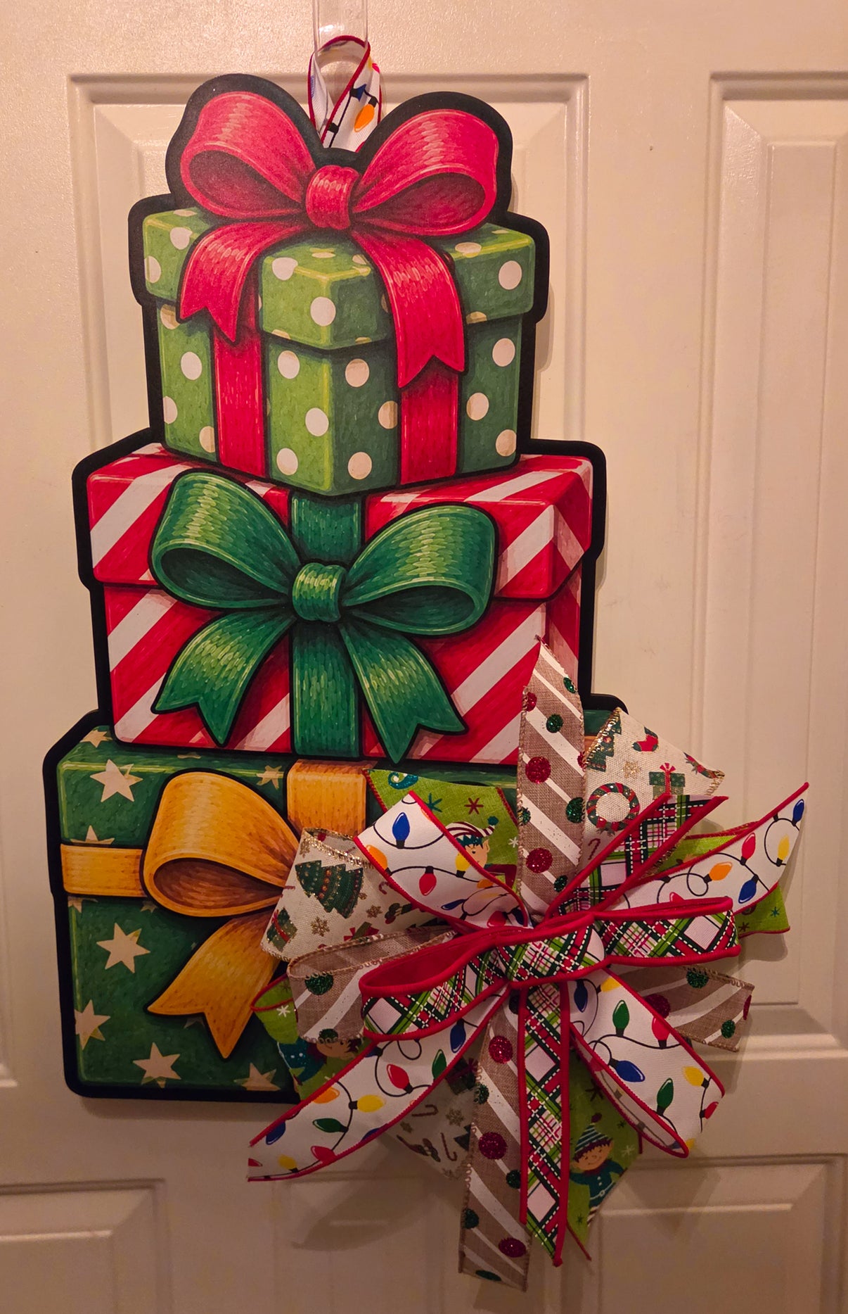 Stacked with Christmas Cheer door hanger featuring three colorful wrapped presents with painted bows and a layered Christmas ribbon bow.