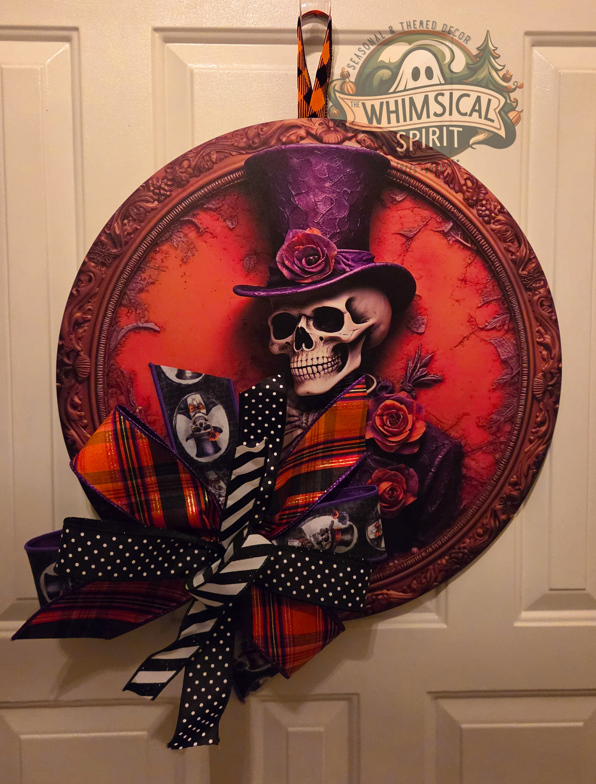 The Dapper Departed gothic skeleton birch wood door hanger with an ornate portrait frame, crimson roses, and a large Halloween bow