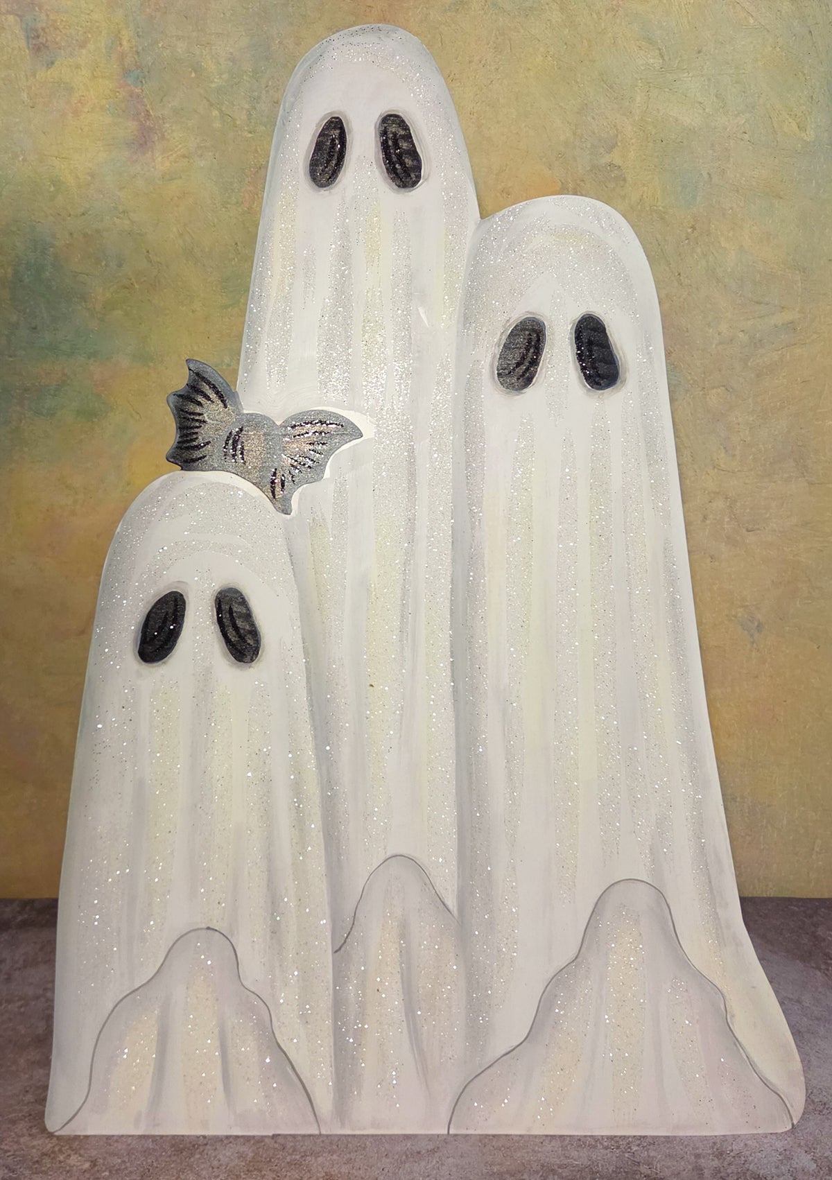 The Ghostly Gathering Halloween metal art featuring three glittering white sheet ghosts with black eyes and a silvery bat.