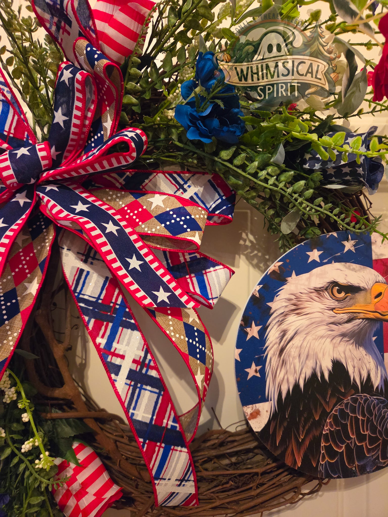 Decorative wreath with American flag ribbon, eagle emblem, and 'Whimsical Spirit' label.