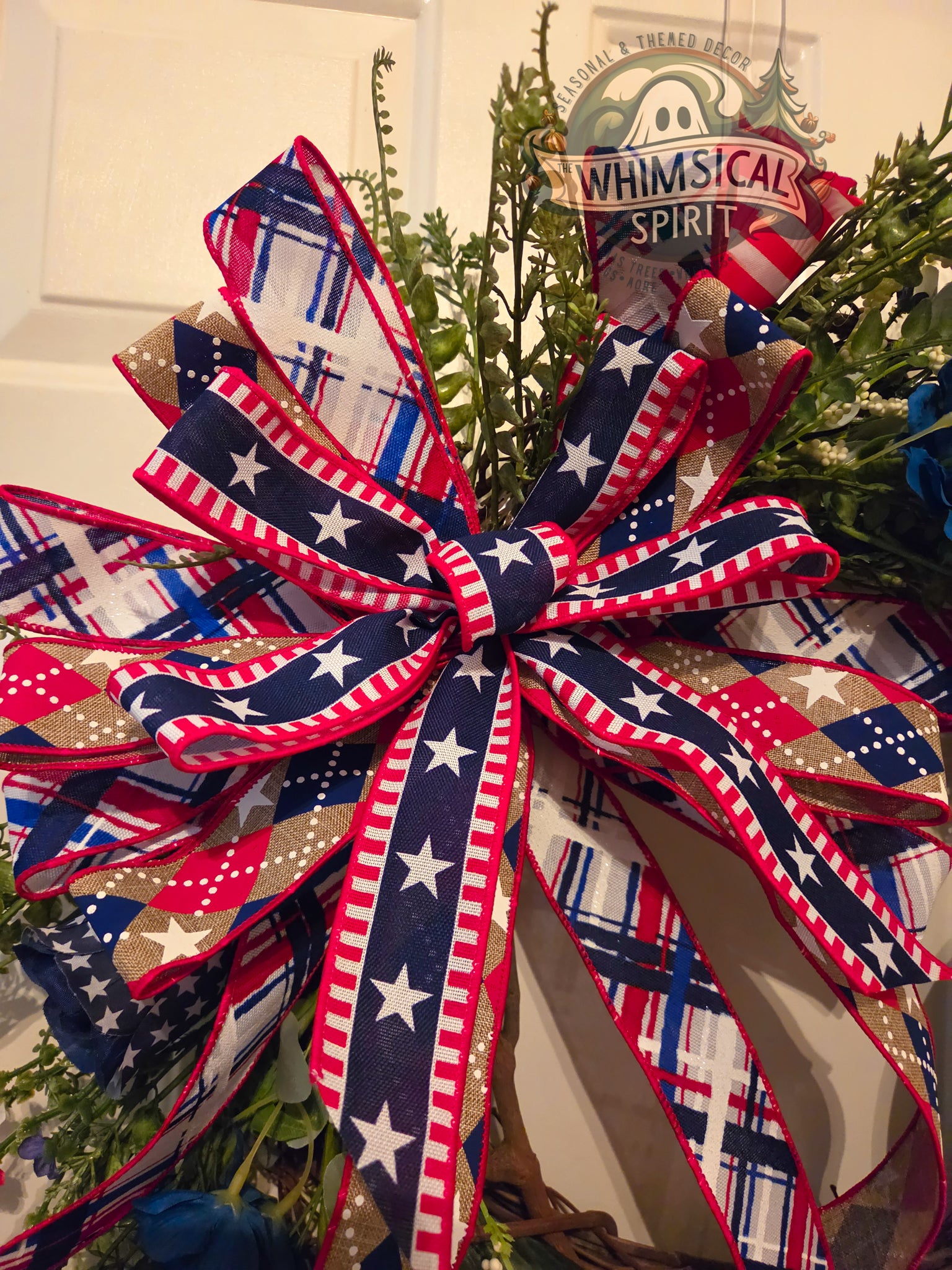 Decorative bow with patriotic design in front of a door with 'Whimsical Spirit' sign.