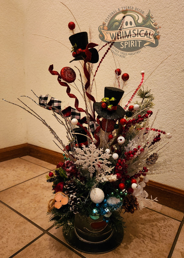 Decorative Christmas arrangement with top hats and ornaments on a tiled floor, featuring 'Whimsical Spirit' logo.