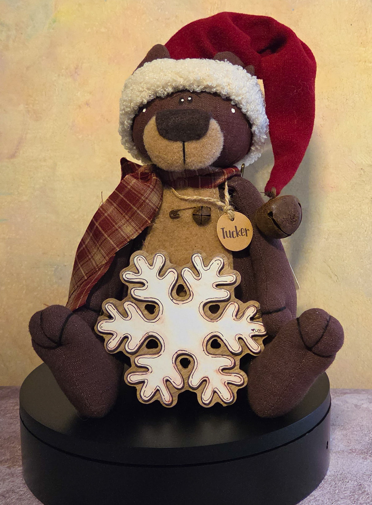 Tucker the Teddy Bear winter soft sculpture shelf sitter with red Santa hat, plaid scarf, snowflake accent, name tag, and cozy teddy bear details.