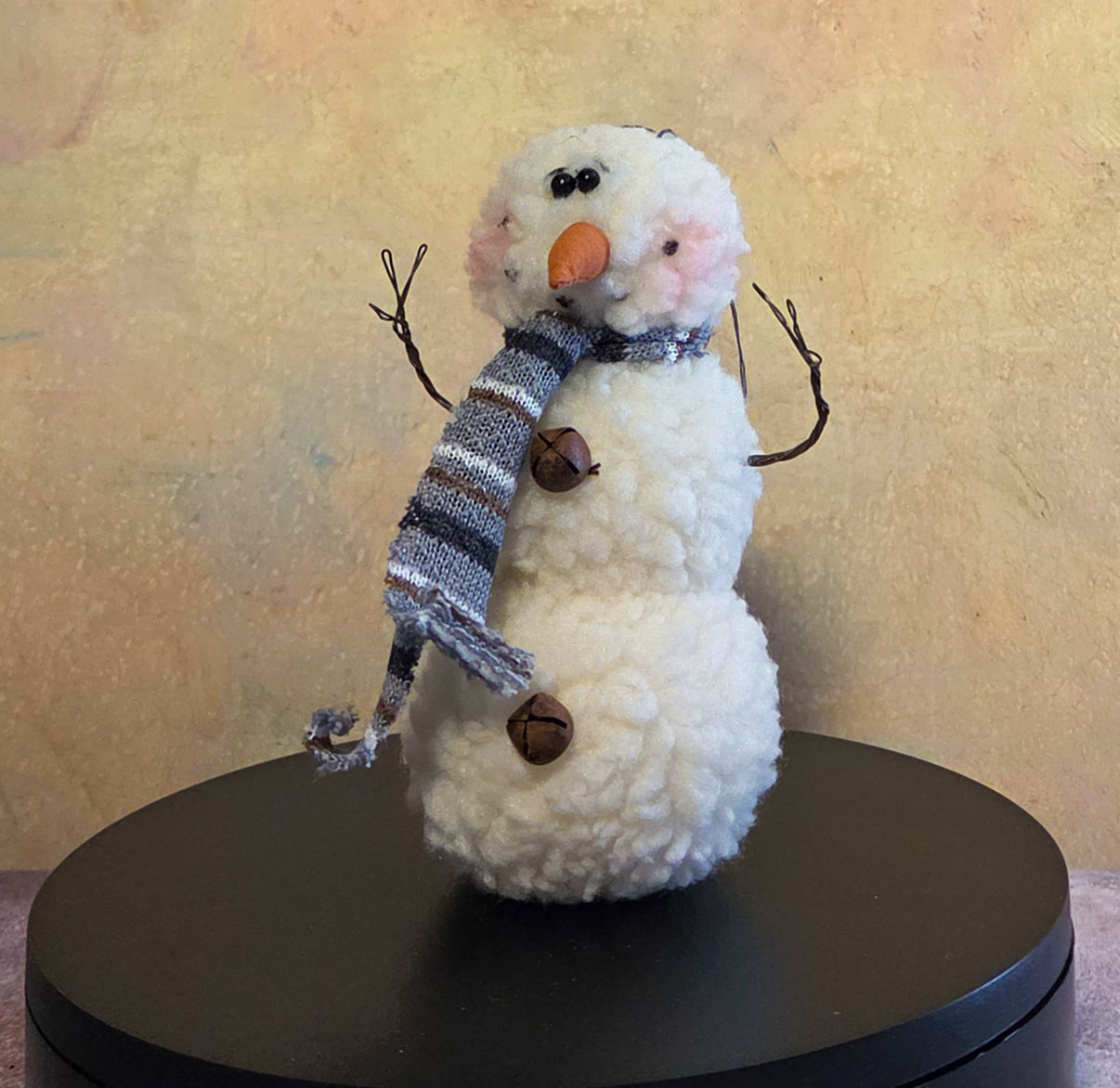 Wooly Snowman plush Christmas ornament with fuzzy white body, gray striped scarf, carrot nose, twig arms, and button details.