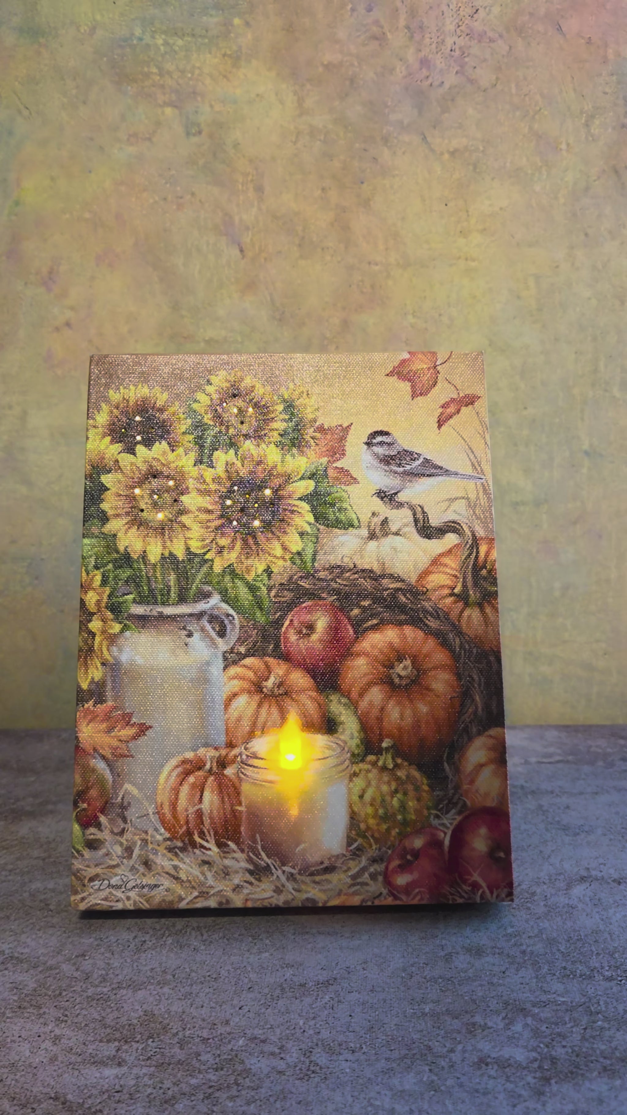 Video showing the light-up function on Bountiful Harvest, a fall tabletop canvas featuring sunflowers, pumpkins, apples, a glowing candle, autumn leaves, and a small bird.