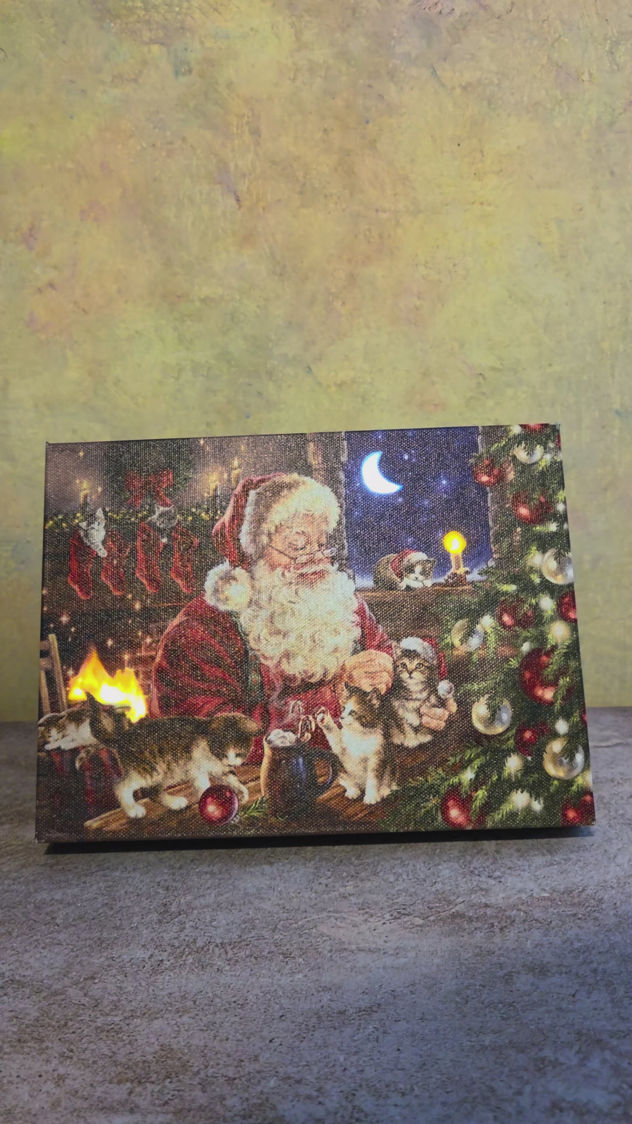 Video showing the light-up function on Santa’s Furry Friends, a Christmas tabletop canvas featuring Santa with cats, a cozy fireplace, stockings, a decorated tree, and glowing holiday details.
