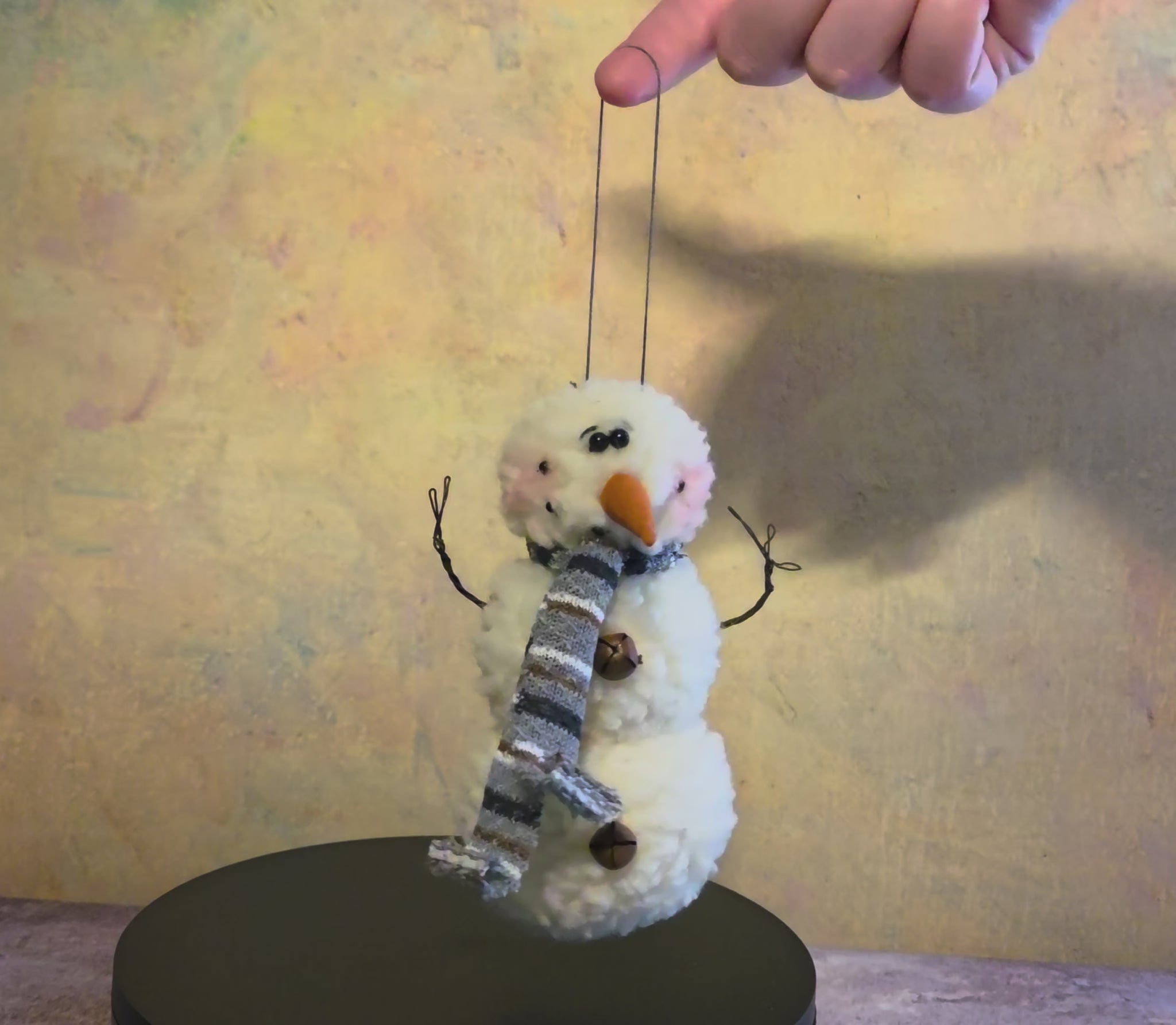 Short video of the Wooly Snowman plush Christmas ornament showing its fuzzy white texture, gray striped scarf, carrot nose, twig-style arms, button details, and hanging loop for Christmas tree decorating.