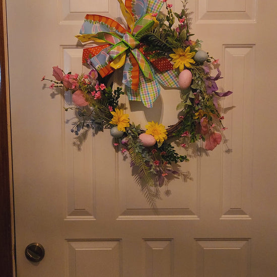 Video of Decorative wreath with colorful flowers and a large bow on a door