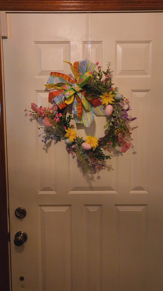 Video of Decorative wreath with colorful flowers and a large bow on a door