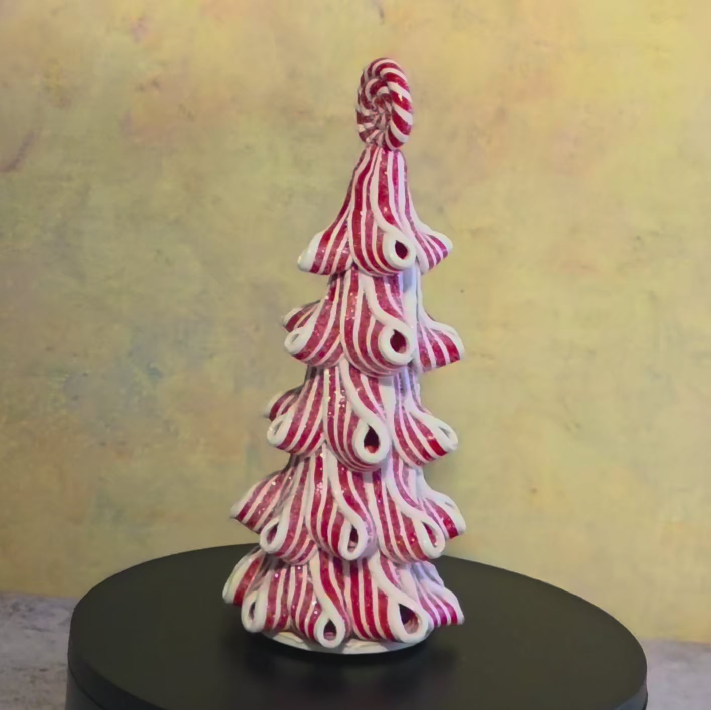 Short turntable video showing the medium Peppermint Twirl Trees rotating to display their red-and-white ribbon design, candy toppers, and lighted details.