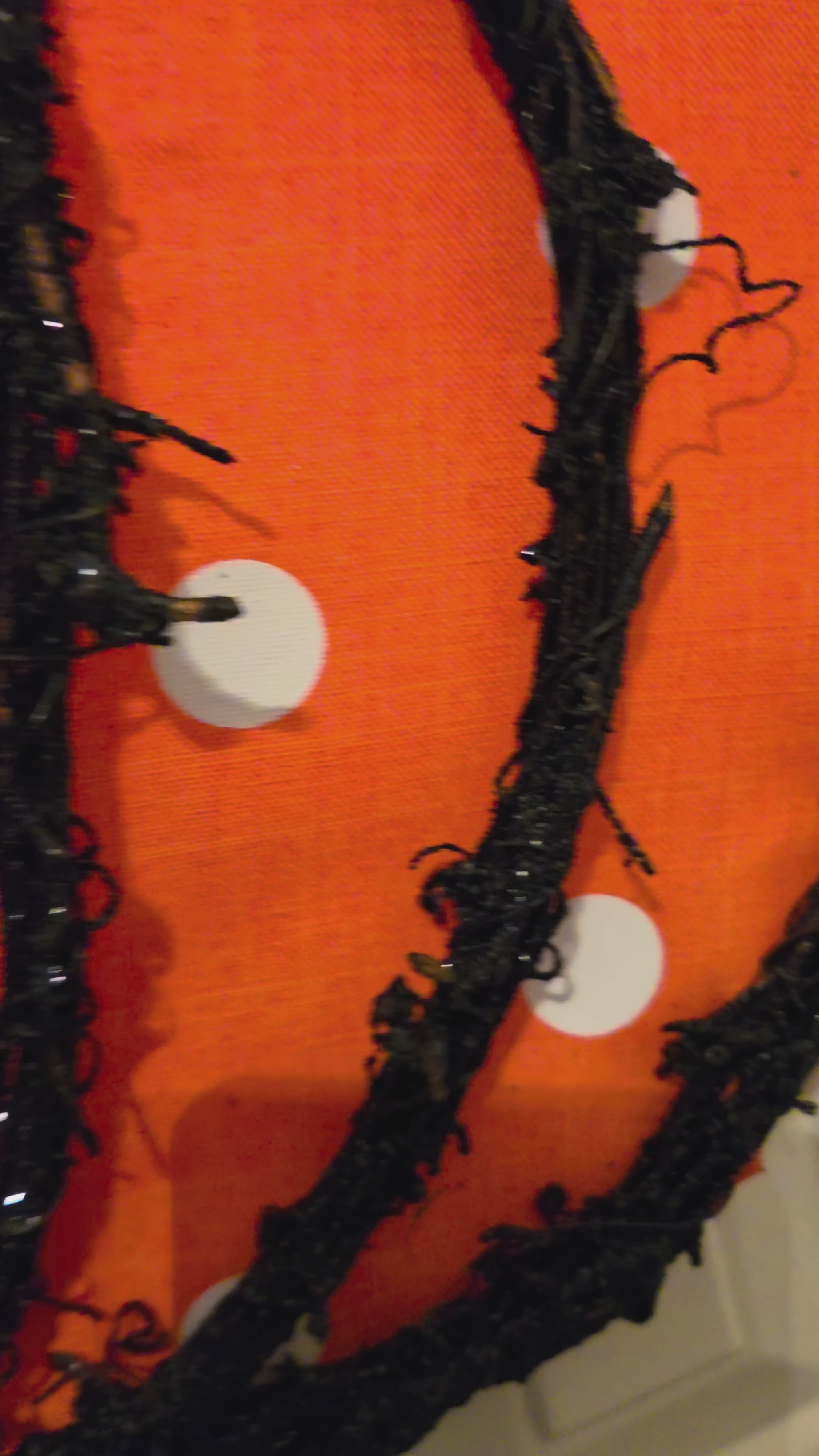 Closeup video of a handmade Halloween and fall double pumpkin door hanger, showing the black plaid pumpkin, orange polka dot pumpkin, textured trim, layered Halloween bow, and full finished design.