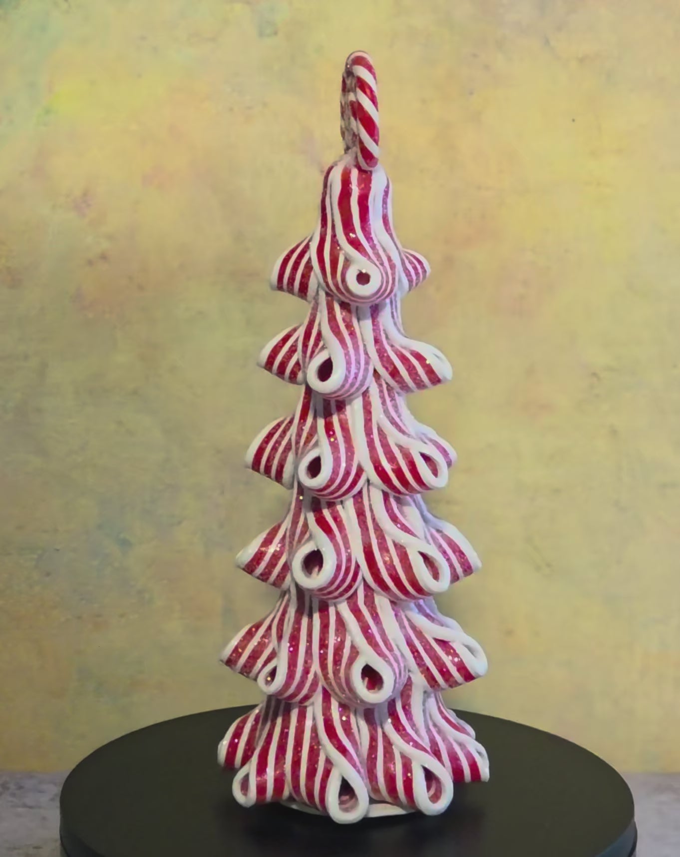 Short turntable video showing the tall Peppermint Twirl Trees rotating to display their red-and-white ribbon design, candy toppers, and lighted details.