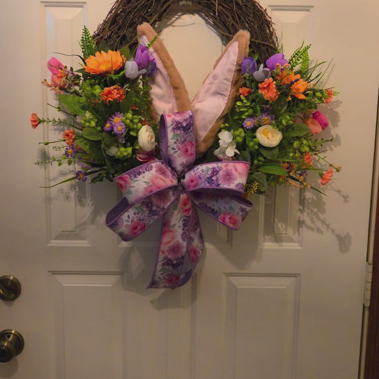 Decorative wreath with flowers and bunny ears on a door