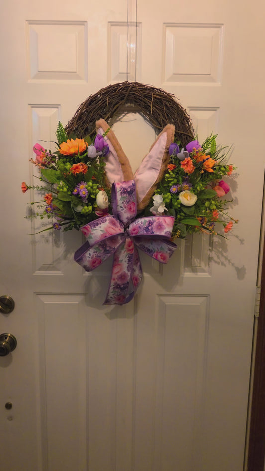 Decorative wreath with flowers and bunny ears on a door