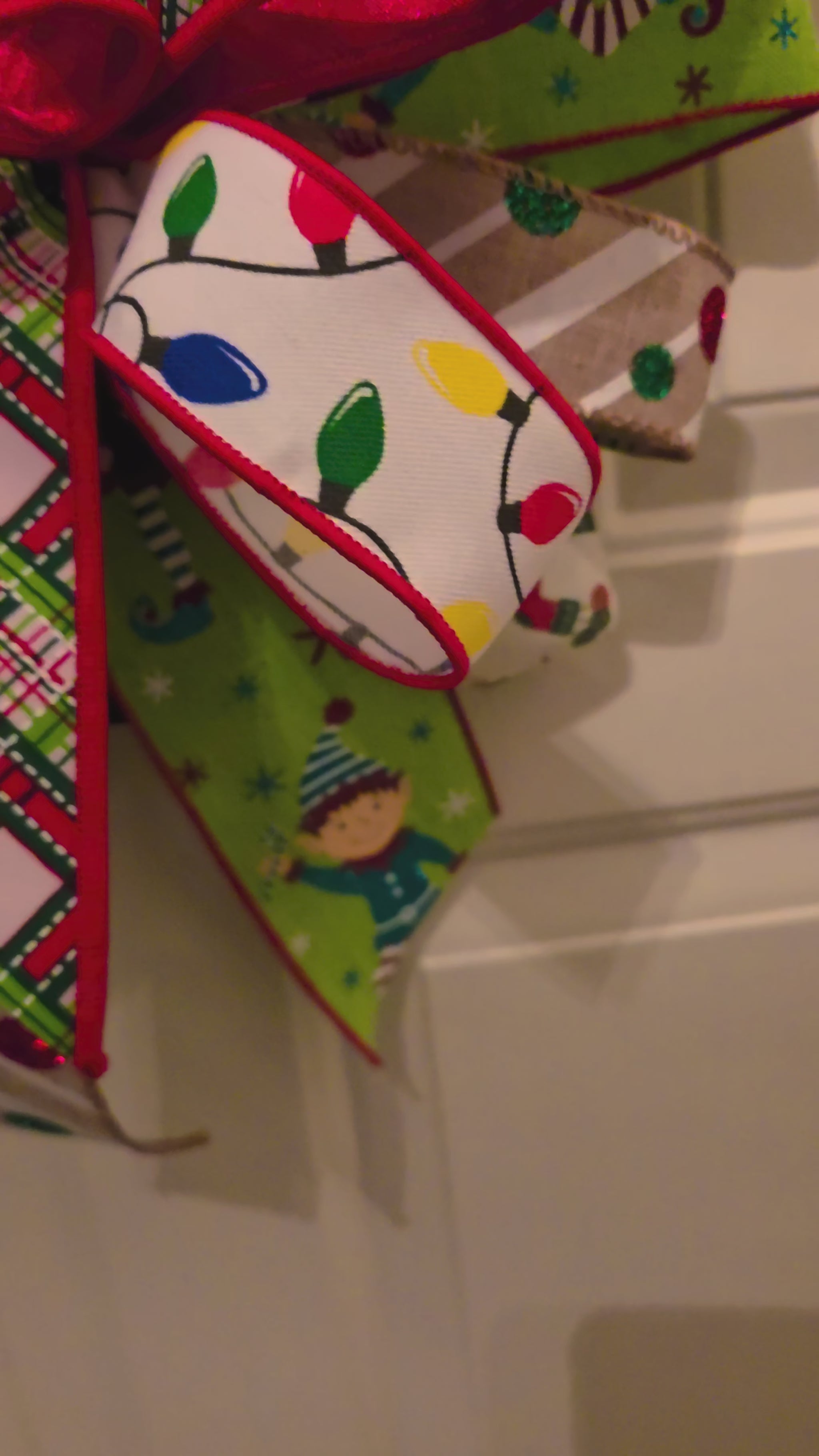 Video showing the details of the Stacked with Christmas Cheer door hanger, including the painted presents, decorative bows, and layered holiday ribbons.