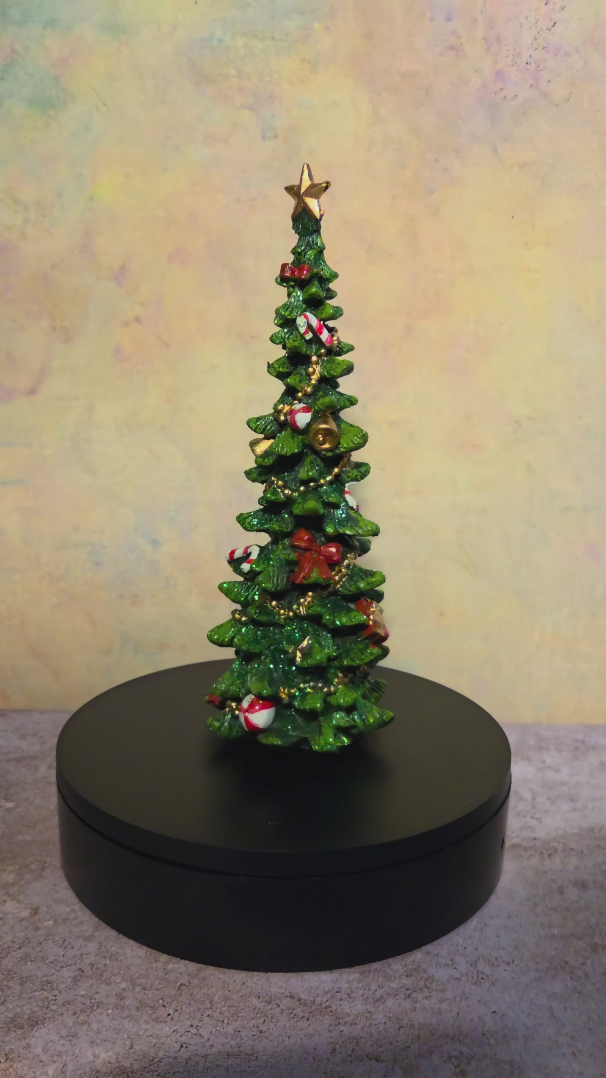 Turntable video showing all sides of the medium resin Christmas tree figurine and its detailed ornaments, bows, and gold garland.
