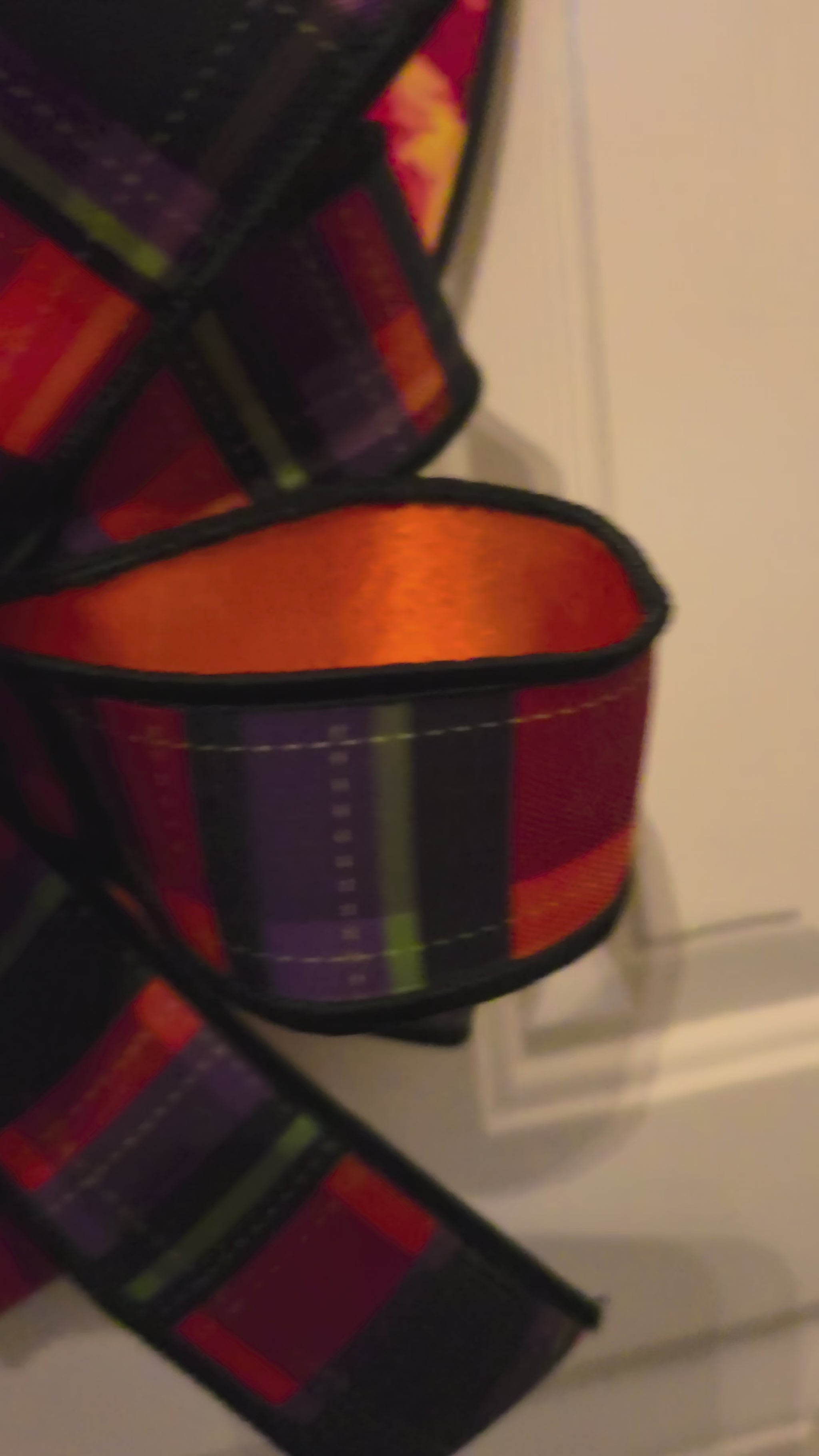 Video showing a Halloween black cat witch door hanger with stained glass artwork and an orange plaid bow displayed on a front door.