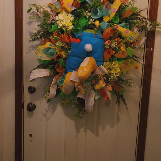 Colorful wreath with flowers and ribbons on a door