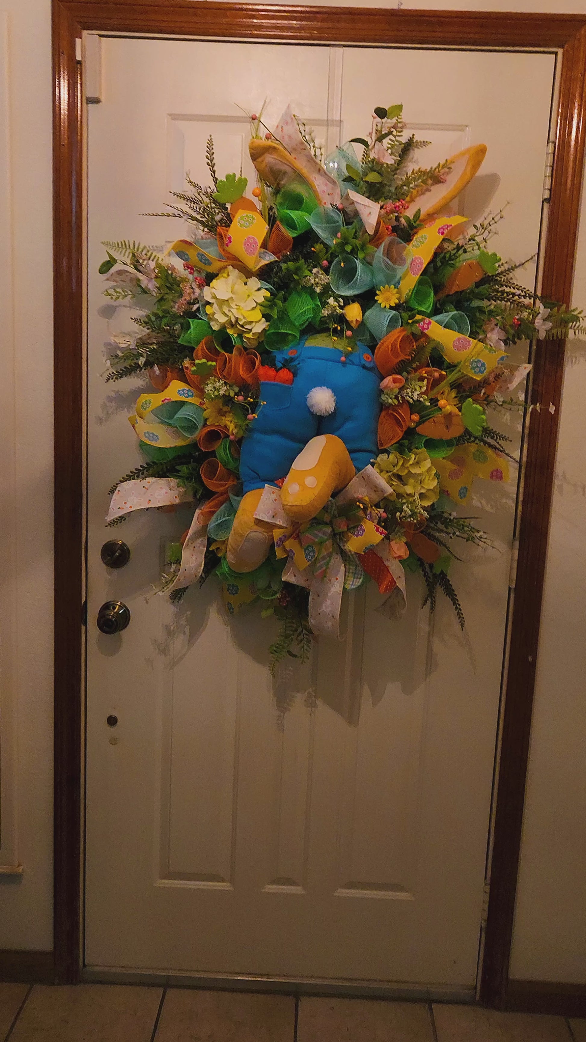 Colorful wreath with flowers and ribbons on a door