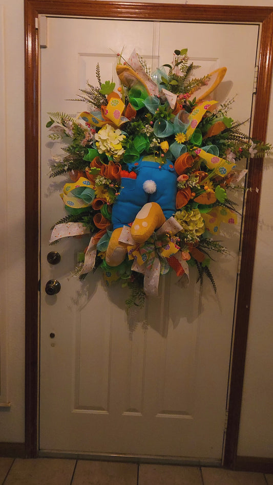 Colorful wreath with flowers and ribbons on a door